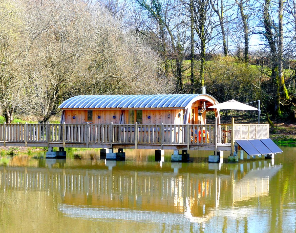 Hébergement insolite en cabane flottante, avec terrasse sur un lac paisible.
