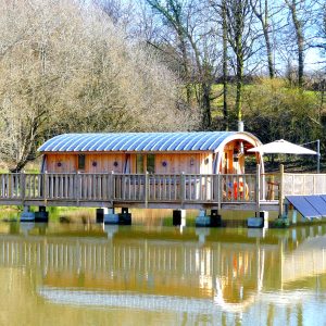 Hébergement insolite en cabane flottante, avec terrasse sur un lac paisible.