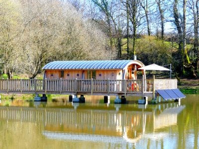 Hébergement insolite en cabane flottante, avec terrasse sur un lac paisible.