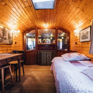 Hébergement insolite : roulotte en bois avec lit douillet et décor chaleureux.