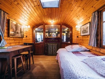 Hébergement insolite : roulotte en bois avec lit douillet et décor chaleureux.