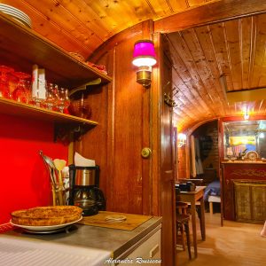 Hébergement insolite en cabane avec intérieur en bois chaleureux et cuisine équipée.