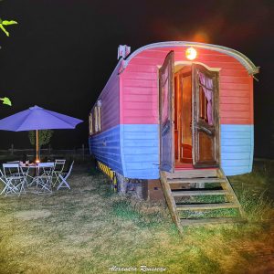 Charmante roulotte colorée avec terrasse et table, idéale pour une nuit étoilée.