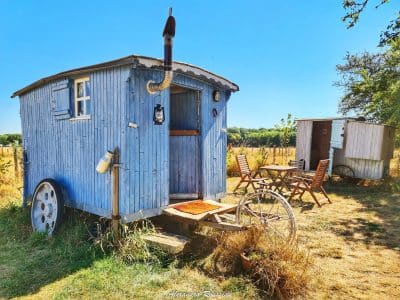 Charmante roulotte bleue entourée de verdure, idéale pour un séjour insolite.