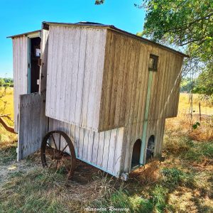 Hébergement insolite : une roulotte en bois au milieu dun champ verdoyant.