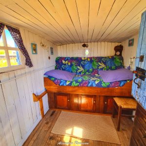 Cabane cosy avec lit coloré et rideaux fleuris, idéale pour un séjour unique.