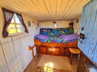 Cabane cosy avec lit coloré et rideaux fleuris, idéale pour un séjour unique.