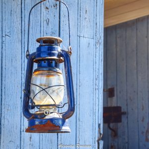 Lanterne vintage accrochée à un mur bleu, créant une ambiance chaleureuse.