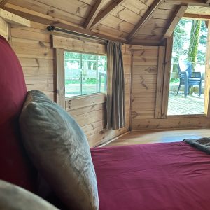 Intérieur dun hébergement insolite en bois, lit confortable et vue sur la nature.