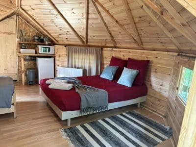 Cabane en bois dans le Pays de la Loire, lit douillet avec draps rouges et décor chaleureux.