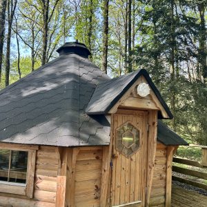 Cabane en bois ronde, nichée dans la forêt verdoyante des Pays de la Loire.