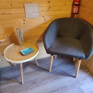 Hébergement insolite en Bourgogne : intérieur en bois avec fauteuil moderne et table ronde.