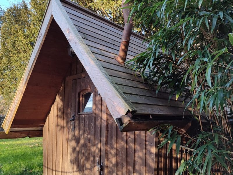 Cabane en bois à Bourgogne, entourée de verdure et dun chemin en bois.