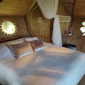 Cabane en bois à Bourgogne, lit douillet avec décor naturel et fenêtres originales.