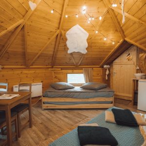 Cabane en bois cosy avec lit double, décor chaleureux et lumière tamisée.