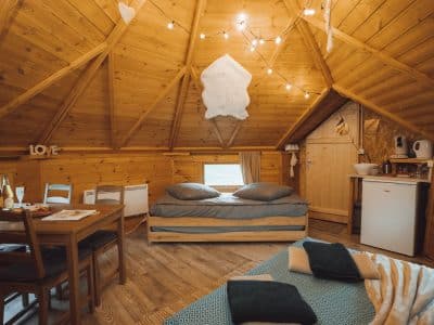Cabane en bois cosy avec lit double, décor chaleureux et lumière tamisée.