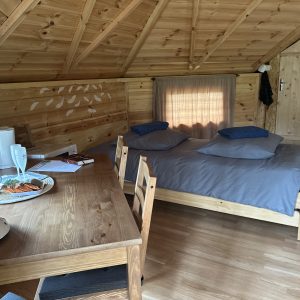 Cabane en bois chaleureuse avec lit double et coin repas accueillant.
