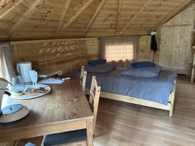 Cabane en bois chaleureuse avec lit double et coin repas accueillant.