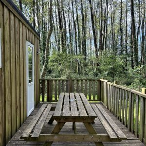 Cabane en bois dans les Pays de la Loire, avec terrasse en bois entourée darbres.
