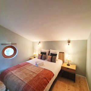 Chambre cosy dans un hébergement insolite avec fenêtre ronde à Bourgogne-Franche-Comté.