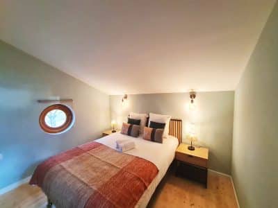 Chambre cosy dans un hébergement insolite avec fenêtre ronde à Bourgogne-Franche-Comté.
