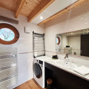 Salle de bain moderne dun hébergement insolite en Bourgogne-Franche-Comté, avec fenêtre ronde.