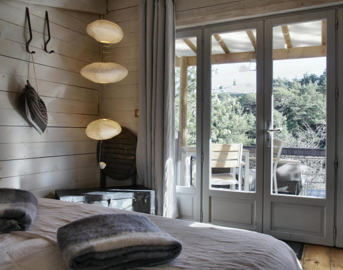 Chalet en bois avec vue sur la nature, lumière douce et décoration chaleureuse.