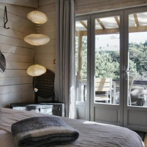 Chalet en bois avec vue sur la nature, lumière douce et décoration chaleureuse.