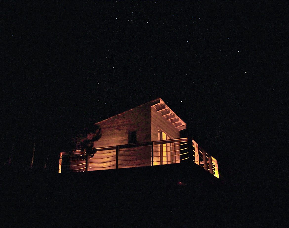 Cabane en bois avec terrasse illuminée sous un ciel étoilé en Provence-Alpes-Côte dAzur.
