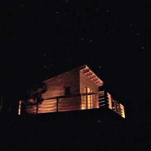 Cabane en bois avec terrasse illuminée sous un ciel étoilé en Provence-Alpes-Côte dAzur.