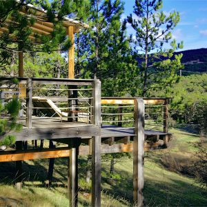 Cabane perchée en bois avec terrasse, entourée de verdure en Provence-Alpes-Côte dAzur.