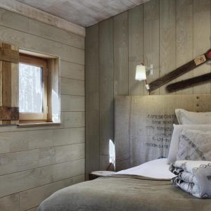 Chalet en bois avec un lit douillet et des décorations en bois rustiques.