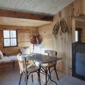 Cabane en bois dans les Alpes, intérieur chaleureux avec table et chaises vintage.
