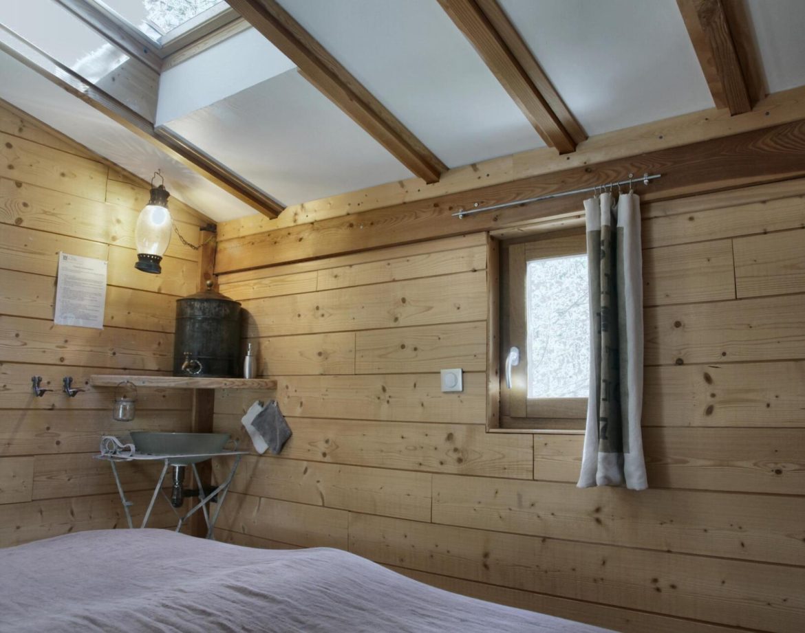 Cabane en bois chaleureuse avec poutres apparentes et lumière naturelle.