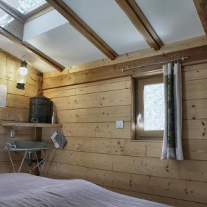 Cabane en bois chaleureuse avec poutres apparentes et lumière naturelle.