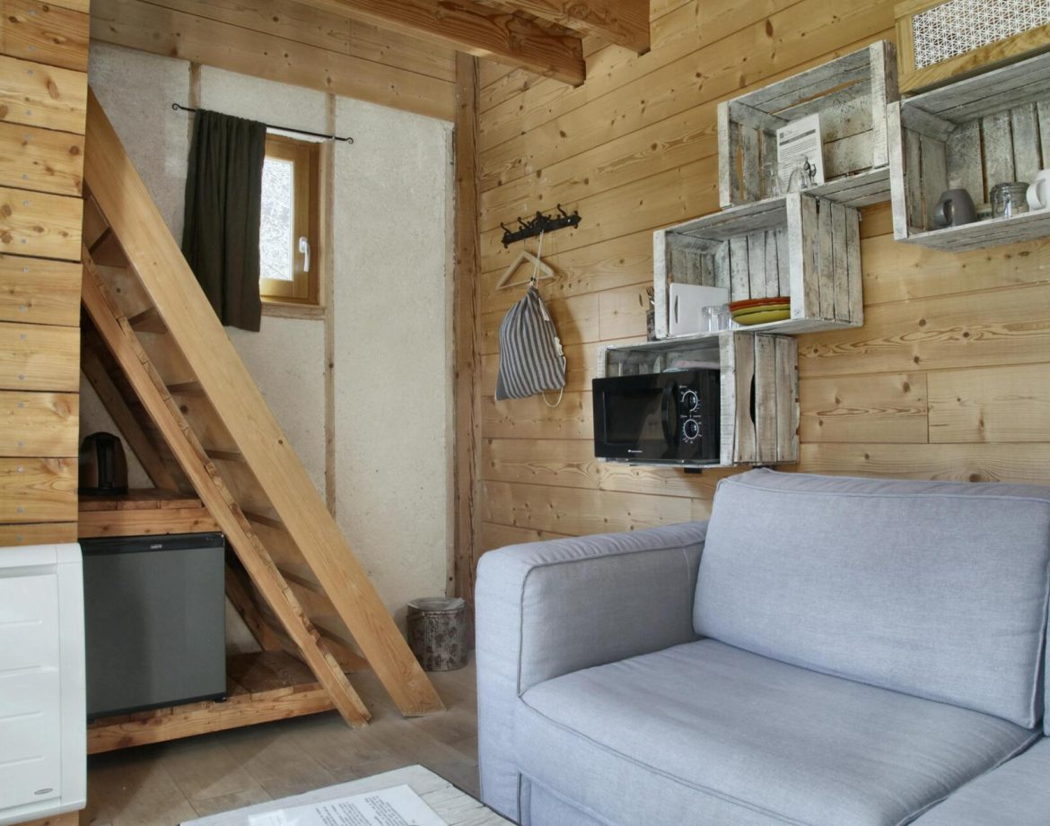 Cabane en bois cosy avec un coin salon et des étagères rustiques.