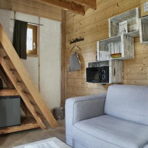 Cabane en bois cosy avec un coin salon et des étagères rustiques.
