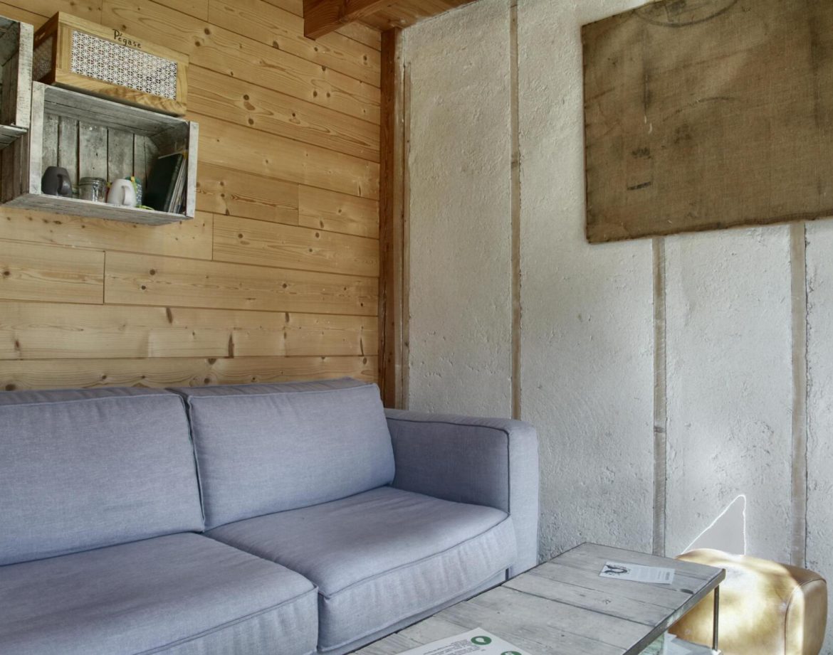 Cottage en bois avec un canapé confortable et des étagères rustiques.