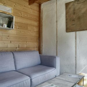 Cottage en bois avec un canapé confortable et des étagères rustiques.