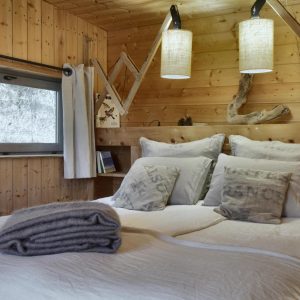 Chalet en bois chaleureux avec lit douillet et luminaires suspendus.
