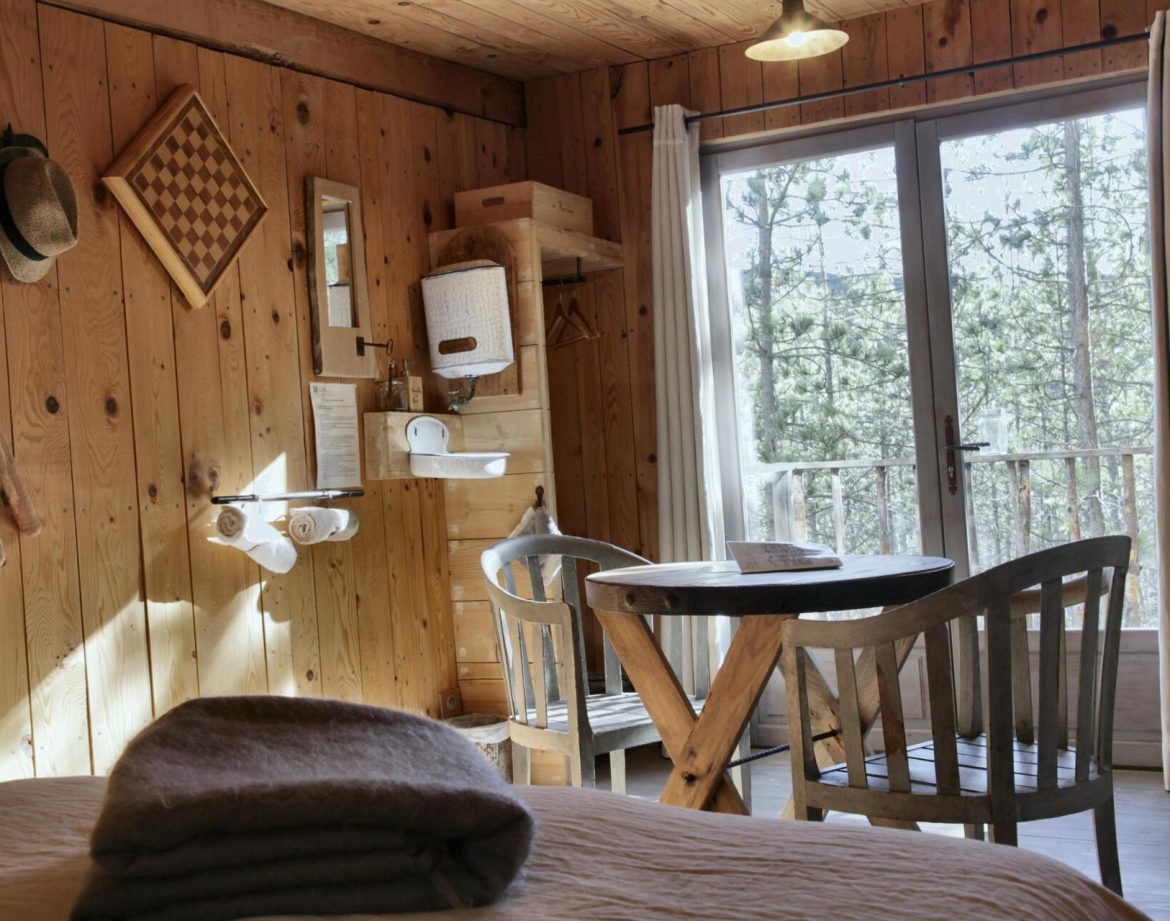 Cabane en bois chaleureuse avec vue sur la nature, table en bois et décor rustique.
