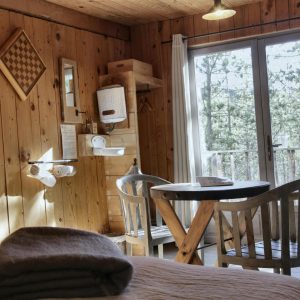 Cabane en bois chaleureuse avec vue sur la nature, table en bois et décor rustique.