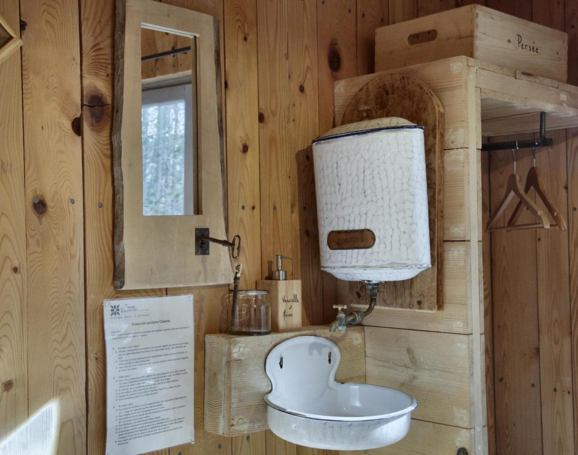 Intérieur dun hébergement insolite en bois avec lavabo vintage et miroir.
