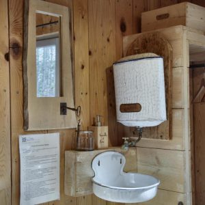 Intérieur dun hébergement insolite en bois avec lavabo vintage et miroir.