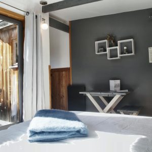 Chalet moderne en bois avec vue sur la nature, lit confortable et décor épuré.