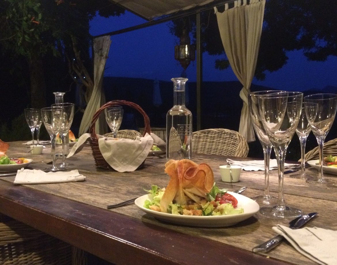 Table élégamment dressée en extérieur, avec des plats raffinés sous un ciel étoilé.