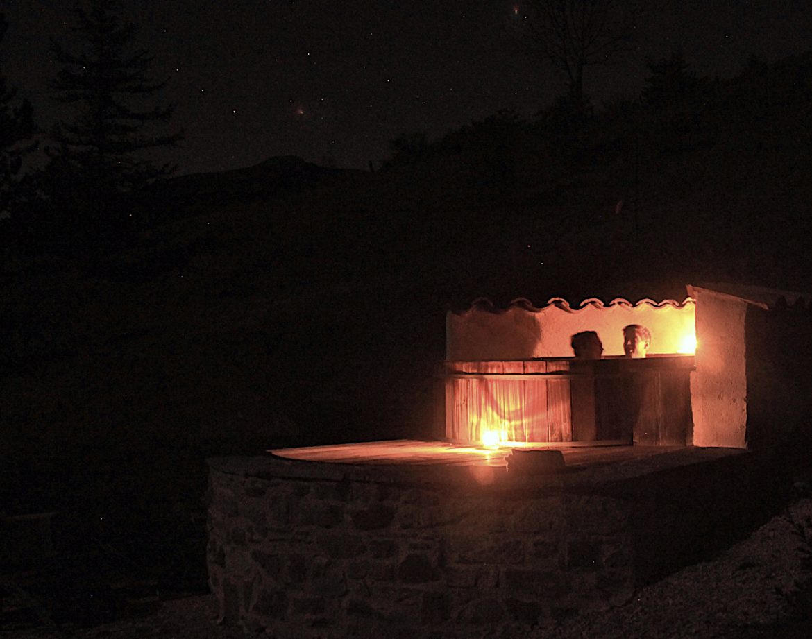 Hébergement insolite en pierre avec une terrasse éclairée par des bougies, sous un ciel étoilé.
