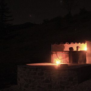 Hébergement insolite en pierre avec une terrasse éclairée par des bougies, sous un ciel étoilé.