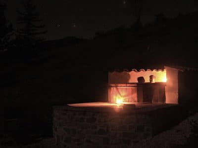 Hébergement insolite en pierre avec une terrasse éclairée par des bougies, sous un ciel étoilé.