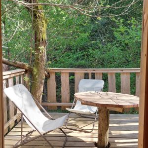 Cabane perchée en Languedoc-Roussillon avec terrasse en bois et chaises confortables.